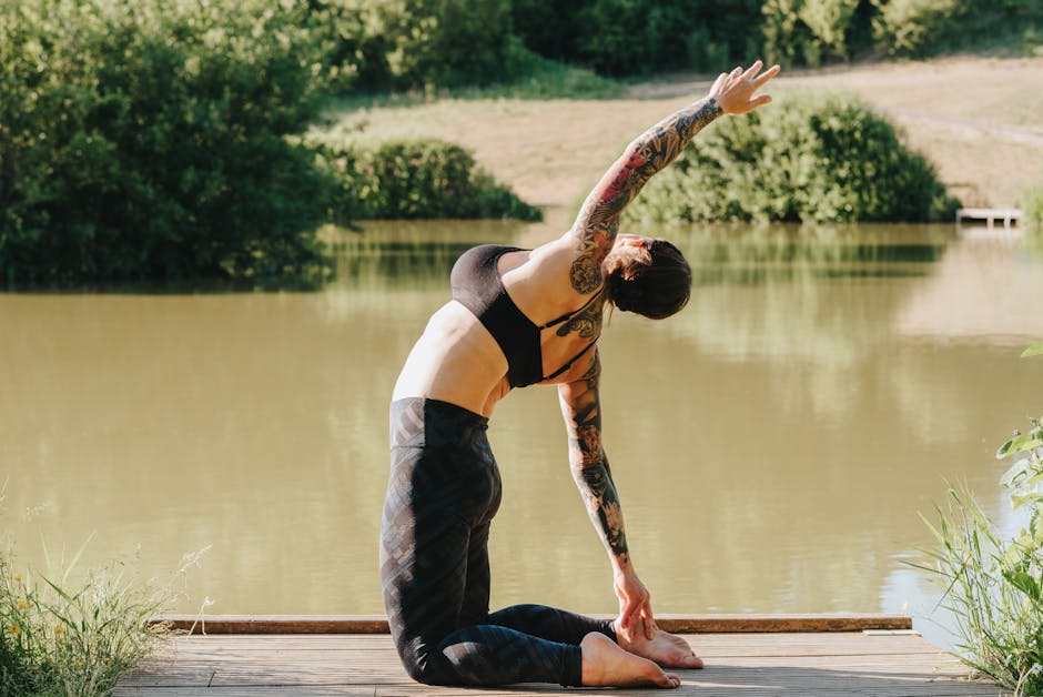 Woman in a peaceful yoga pose on a wooden pier by the lake at sunrise.